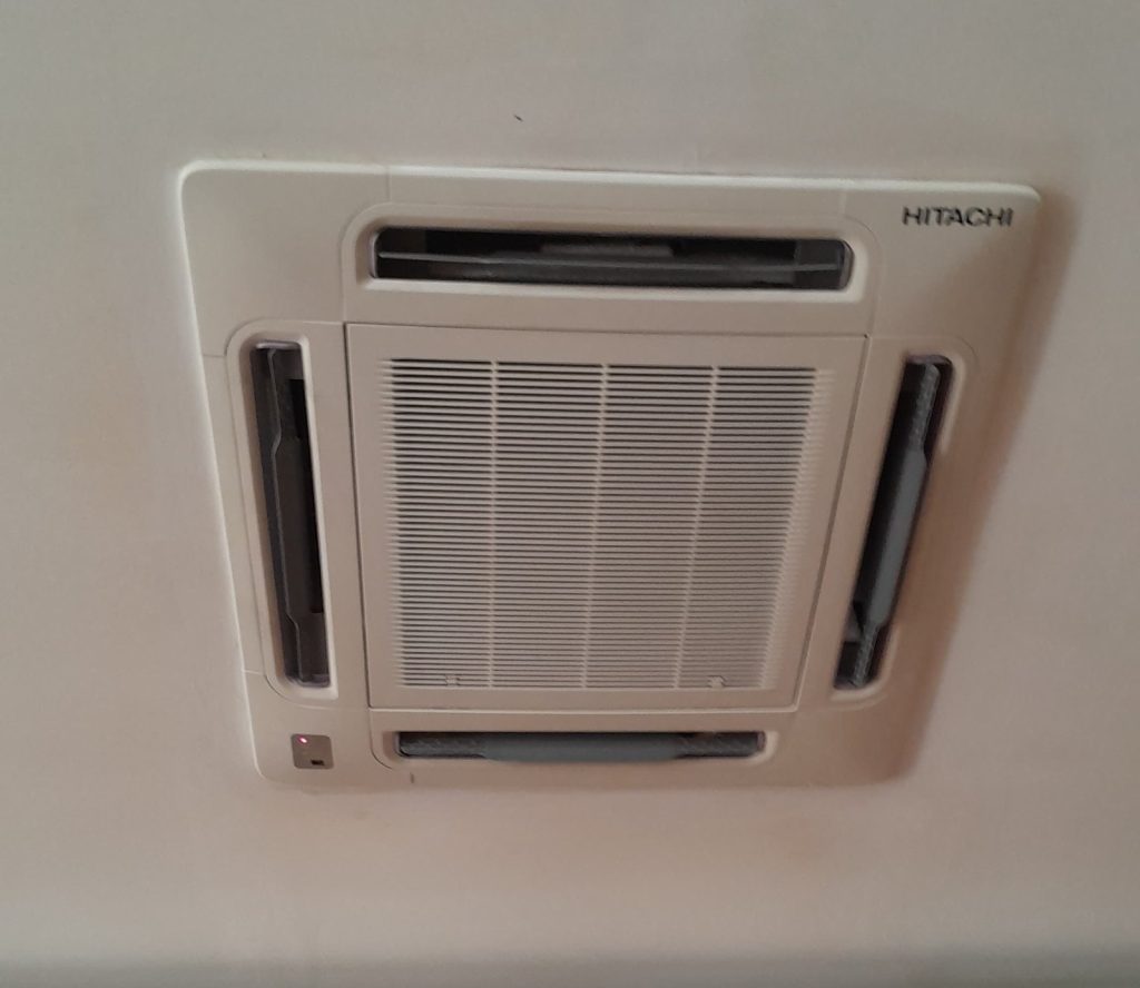 Unidad cassette de aire acondicionado empotrada en el techo de una sala